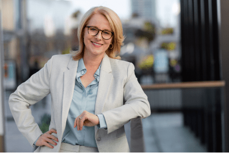 Image of a woman in a professional suit with her hand on her hip, looking at the camera