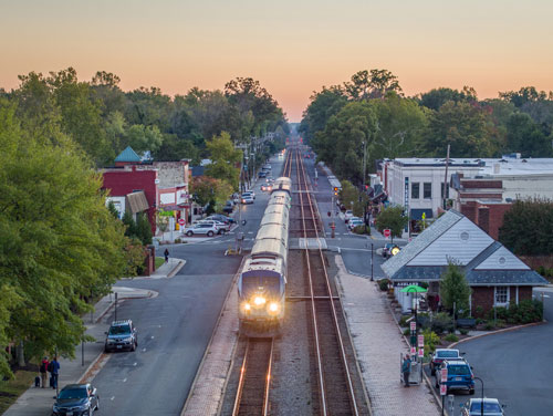 Image of an Amtrak train pulling into a station as the sun begins to rise in the background