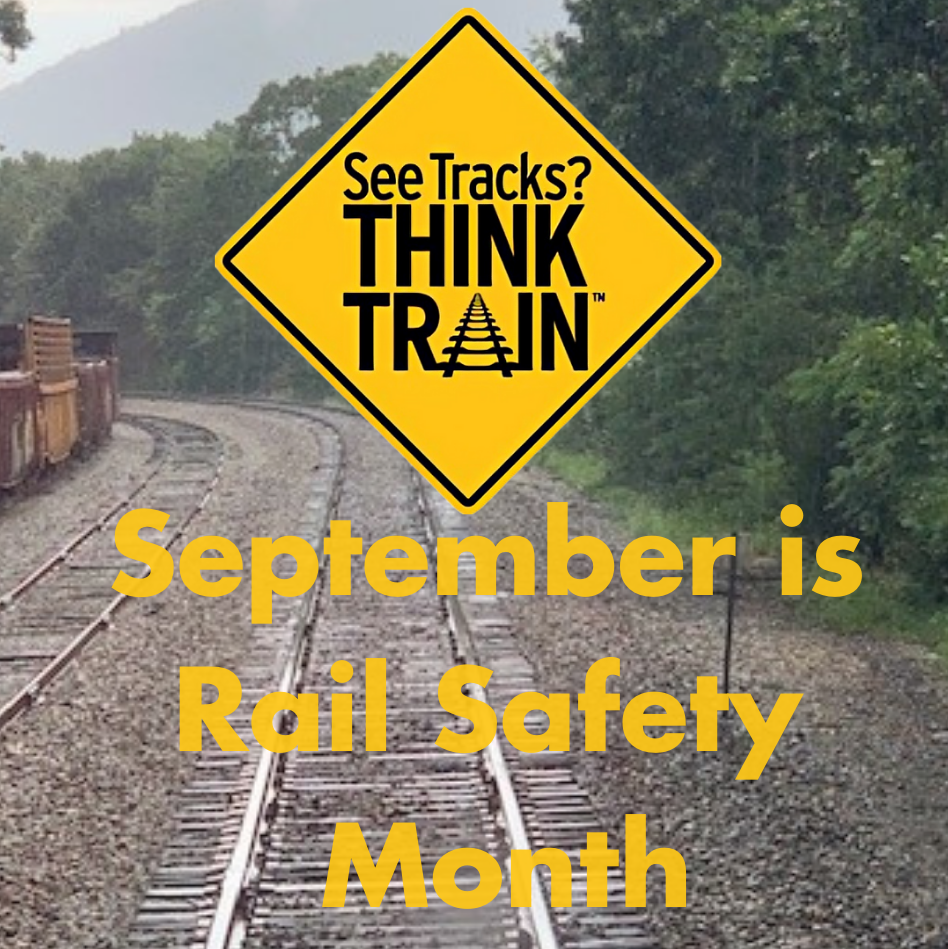 Image of a Cautionary Road Sign that reads See Tracks? Think Train. Printed below is the phrase "September is Rail Safety Month" The sign and phrase are imposed on the foreground of a photo of railroad tracks.
