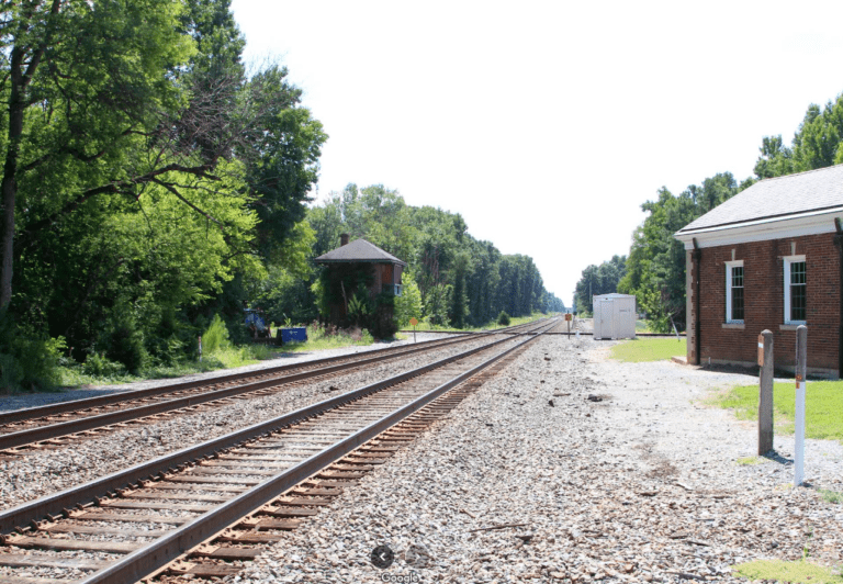 Two railroad tracks on the left and home on the right side of the photo